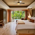 Habitación de hotel con cama king size, decoración cálida y terraza con vista al jardín tropical