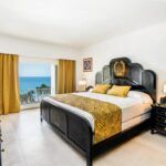Habitación de hotel con cama king size, decoración elegante y vista al mar desde el balcón
